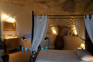 - une chambre avec un lit avec des rideaux et un lavabo dans l'établissement Chambres d'Hôtes Troglodytes Le Clos de L'Hermitage, à Amboise