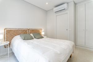 - une chambre blanche avec un grand lit et des draps blancs dans l'établissement Iate Residence, à Portimão