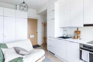 a white kitchen with white cabinets and a white couch at Arctic Taiga Penthouse City Suite in Rovaniemi +7 photos