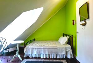 Un dormitorio con una pared verde y una cama en Madie's Place Bed & Breakfast in Santa Rosa, Laguna near Enchanted Kingdom en Santa Rosa