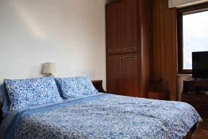 een slaapkamer met een bed met blauwe lakens en een raam bij Bluelake Apartament 1 Omegna in Omegna