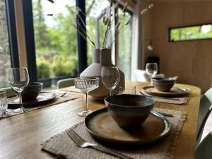 een houten tafel met borden en wijnglazen erop bij FIKA Luxe vakantiewoning voor 4 personen @ Veluwe in Hoenderloo