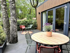 een patio met een houten tafel en stoelen bij FIKA Luxe vakantiewoning voor 4 personen @ Veluwe in Hoenderloo