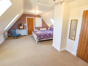 a attic bedroom with a bed and a chair at Saddle Rack Cottage in Louth