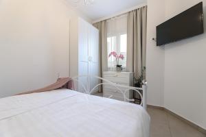 a white bedroom with a bed and a flat screen tv at APARTMAN BORGO MARINA - by the sea in Rijeka