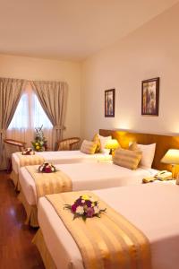 ドバイにあるランドマーク プラザ ホテルの花が飾られたベッド3台が備わるホテルルームです。