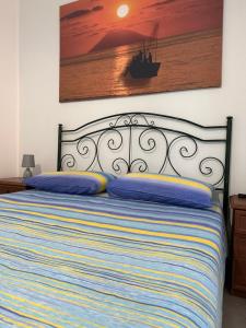 a bed with blue pillows and a painting on the wall at Stefano apartment 2km Tropea boat cruise included in Parghelia