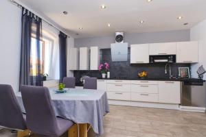 a kitchen with white cabinets and a table with purple chairs at Bella Vista in Cunski
