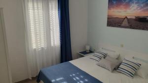 1 dormitorio con 1 cama con almohadas azules y blancas en Apartmani Čulek, en Rukavac