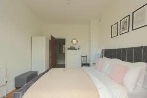 a bedroom with a large white bed with pink pillows at Beautiful one bed garden flat in Muswell hill in London