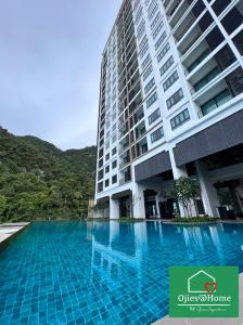 een groot gebouw met een zwembad ervoor bij Ojies Home Sunway Onsen Suites 2BR Theme Park View in Tambun