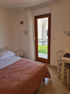 a bedroom with a bed and a table and a window at APARTMANI TONI POCE 2 in Primošten