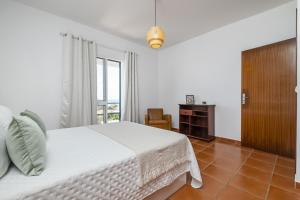 a white bedroom with a bed and a window at Villa Bella Mar by Madeira Sun Travel in Porto Santo