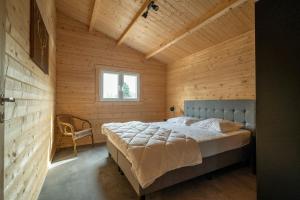 1 dormitorio con 1 cama en una cabaña de madera en Recreatiepark Maas en Bos en Wellerlooi