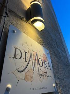 una señal en el lateral de un edificio con luz en Dimora martina, en Loseto