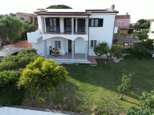 a white house with people sitting on a lawn at Alloggio 2 / Casa Marley Porto Pollo in Barrabisa