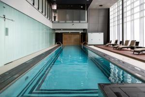 a large swimming pool with blue water in a building at Nasma Luxury Stays - Exquisite Hideaway With Awe-ins Burj Khalifa Views in Dubai