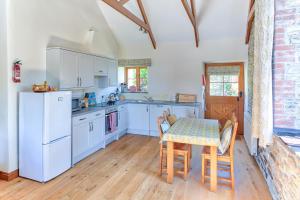 a kitchen with a table and a white refrigerator at Rose Cottage, Tregolls Farm in Saint Wenn
