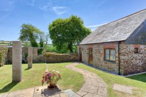 a stone building with a stone pathway next to a yard at Rose Cottage, Tregolls Farm in Saint Wenn