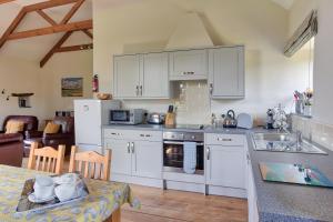 una cocina con armarios blancos y una mesa con sidra de mesa en Rose Cottage, Tregolls Farm, en Saint Wenn