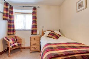 a bedroom with a bed and a chair and a window at Rose Cottage, Tregolls Farm in Saint Wenn