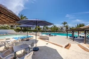 a pool with tables and chairs and an umbrella at Muito Sol in Albufeira