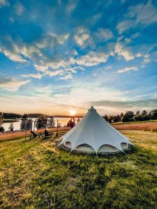 a white tent sitting in the grass in a field at Amberhouse Glempings in Piejūti