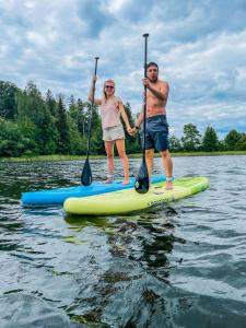 a man and woman on a paddle board on the water at Amberhouse Glempings in Piejūti