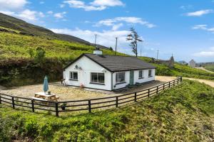 a small white cottage in a field with a fence at Cottage 439 - Clifden in Clifden