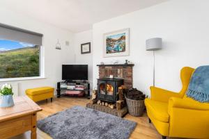 ein Wohnzimmer mit einem Kamin und einem gelben Stuhl in der Unterkunft Cottage 439 - Clifden in Clifden
