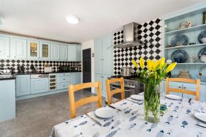 a kitchen with blue cabinets and a table with yellow flowers at Cottage 439 - Clifden in Clifden