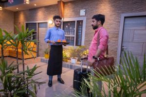 two men standing in front of a house holding a tray of food at Perfectstayz Homes I Luxury Penthouse in Haridwār