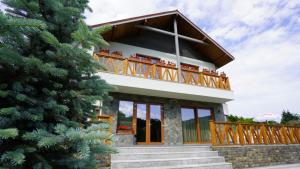 a house with a balcony and a christmas tree at Pensiunea Magic in Băile Govora