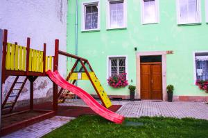 a playground in front of a green building with a slide at Alexandra in Svoboda nad Úpou