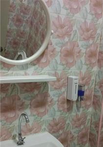 a bathroom with a sink and a mirror and pink flowers at JUNPEN RESORT in Ban Hai Yong