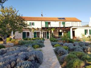 a garden in front of a house with bushes at Villa stone house in Ugljan