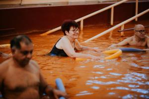 Hotel Tusnad في بايلي توشناد: مجموعة من الناس في الماء مع ألواح ركوب الأمواج