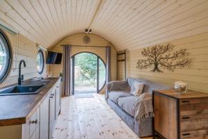 uma cozinha e sala de estar com um sofá numa pequena casa em Laburnum Farm Estate em Alderton
