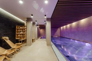 an indoor swimming pool with chairs and a swimming pool at Boutique Hotel Siglisberg in Štiavnické Bane