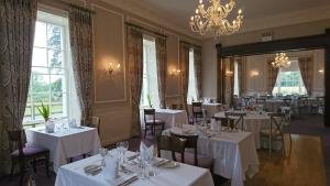 un ristorante con tavoli e sedie bianchi e un lampadario di Leixlip Manor Hotel a Leixlip