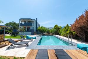 - une piscine avec des chaises et une maison dans l'établissement Infinity Premium Villas Private Pool 3 Bedrooms 5 Bathrooms 2 Kitchens, à Kos