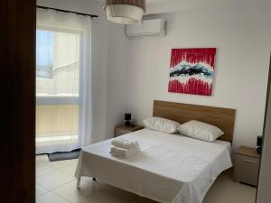 a bedroom with a white bed and a painting on the wall at Privilege suits Swatar in Birkirkara