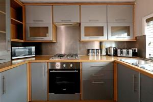 a kitchen with white cabinets and a stove top oven at The Rosary Rest in Norwich