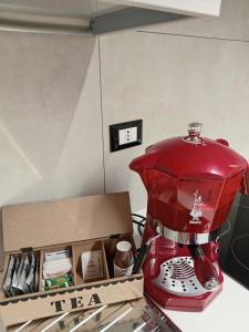 una cafetera roja sentada en un mostrador junto a una caja en B&B al Vicoletto, en Bellante