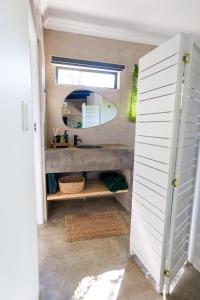 ein Bad mit einem Waschbecken und einem Spiegel im Zimmer in der Unterkunft Veld Villa in Marloth Park
