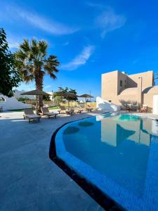 a large swimming pool with chairs and umbrellas at Santorini Villatzio Suites in Mesaria