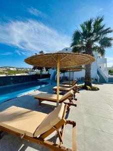 een rij ligstoelen met een parasol en een zwembad bij Santorini Villatzio Suites in Mesariá
