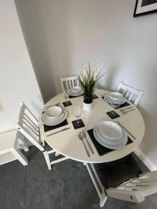 a white table with plates and a plant on it at Storey Apartment in Woodhorn