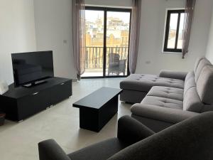 a living room with two couches and a television at Privilege suits Swatar in Birkirkara