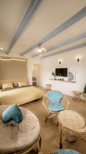 a bedroom with a bed and two chairs and a tv at Tomato Villa & Restaurant in Da Lat